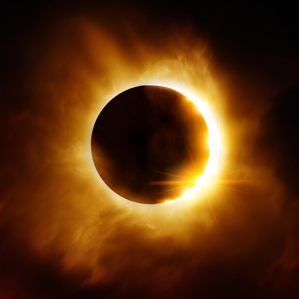 The moon slowly moving in front of the sun during a solar eclipse. The sky around the sun is black.