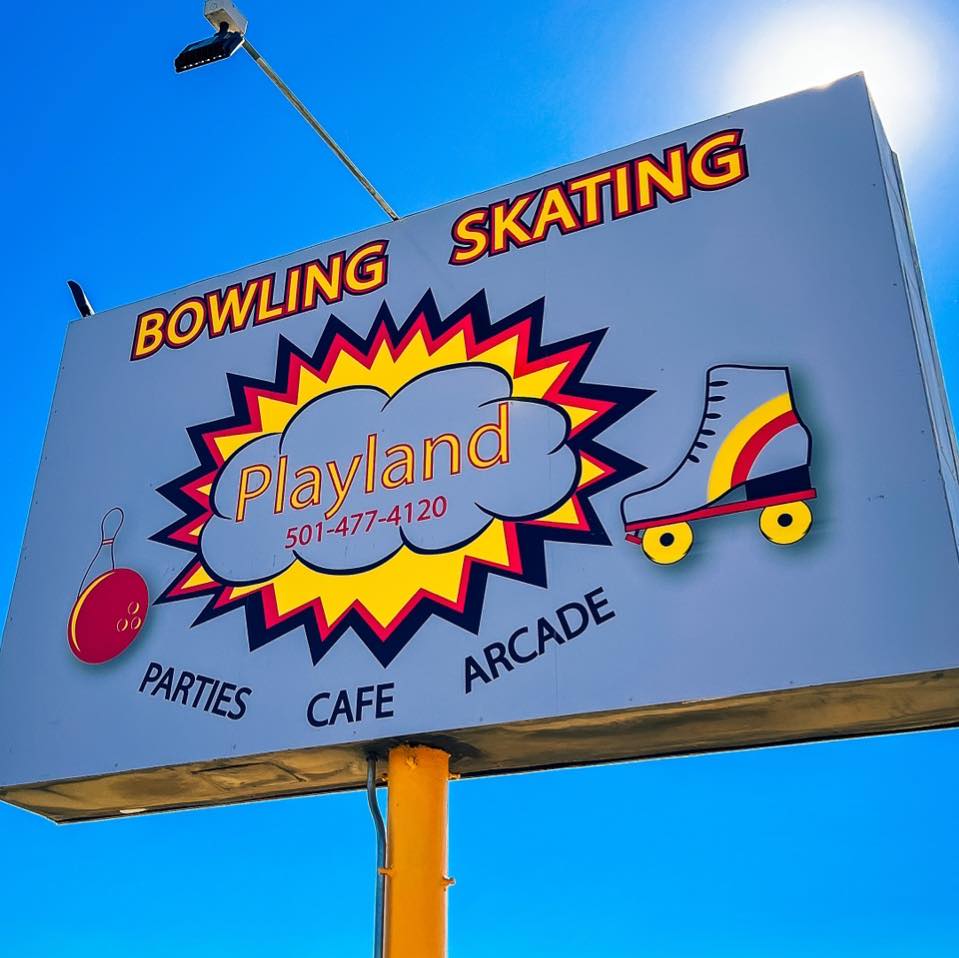 The billboard for Playland. The board says "Bowling Skating" at the top and "Playland" and the phone number are in a cloud in the center. "Parties Cafe Arcade" sits at the bottom.
