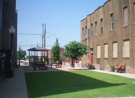 A green space in between two buildings with a patio with picnic tables and a gazebo.